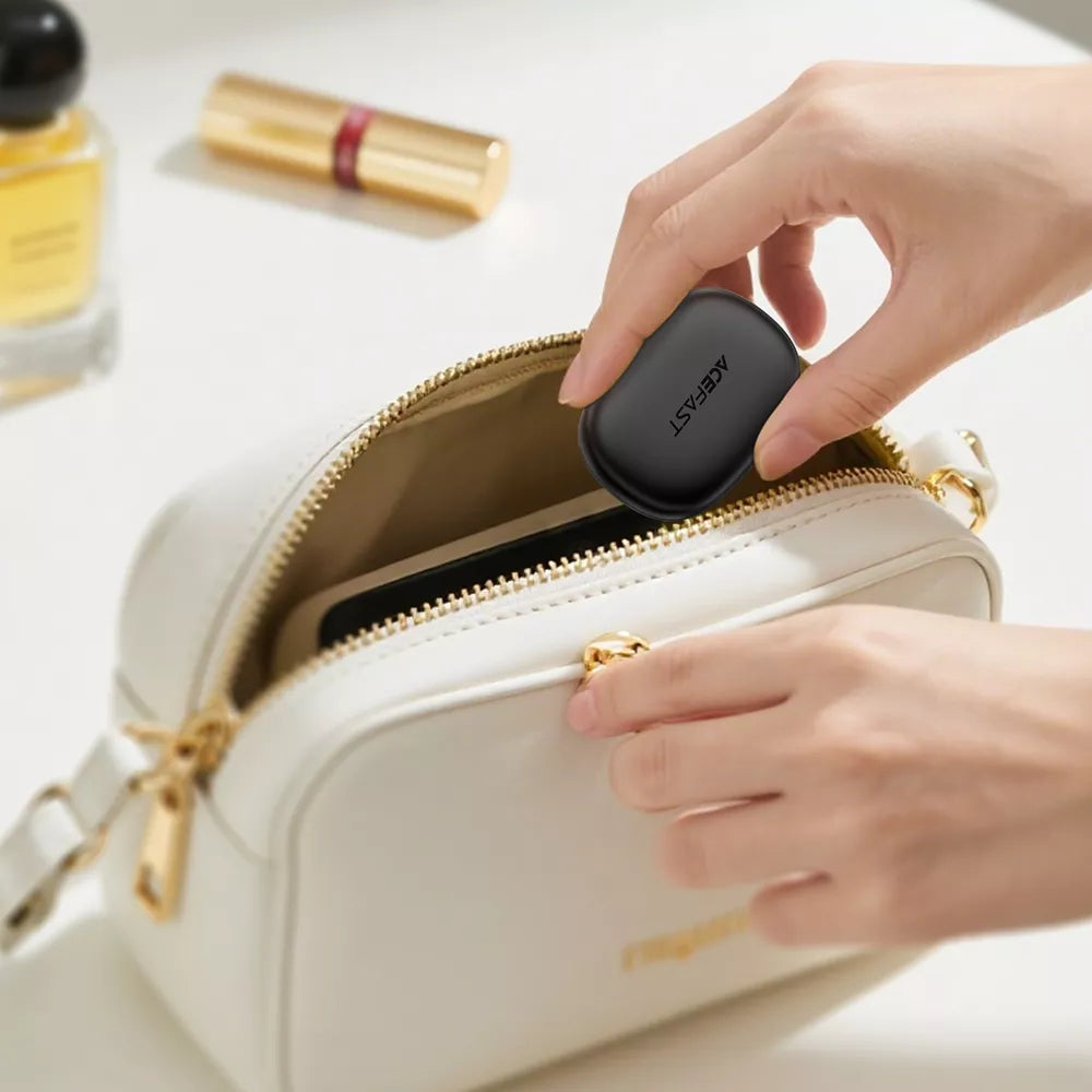 Black Acefast noise cancelling earplugs resting beside their small charging case.